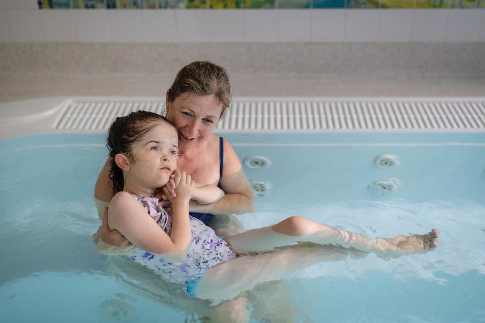Girl in hydrotherapy pool with carer